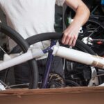 Bicycle workshop, man unpacking box with new bike. Mechanic in uniform fix problems with cycle, professional repairing service