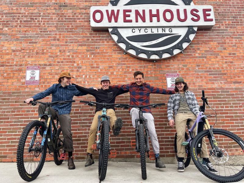 Owenhouse Cycling Team on Bikes in front of the store sign