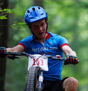 Keegan Walchakm racing on a mountain bike in a green forest