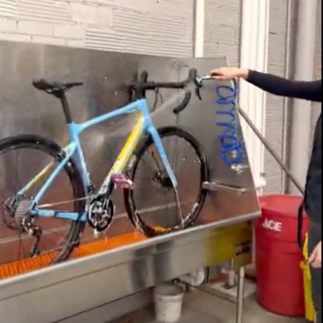 female cleaning a gravel bike in a bike wash station