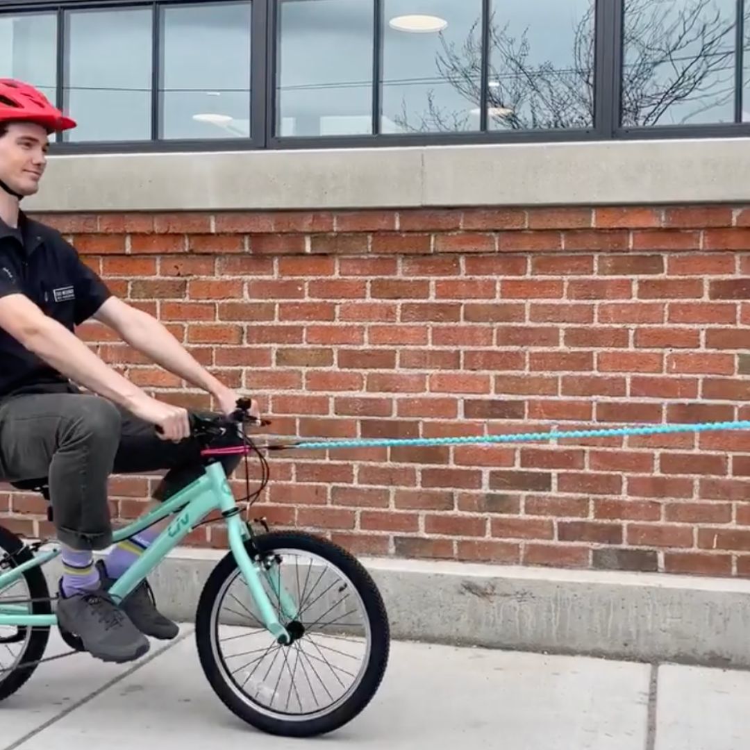 kid on a bike being pulled by a tow rope