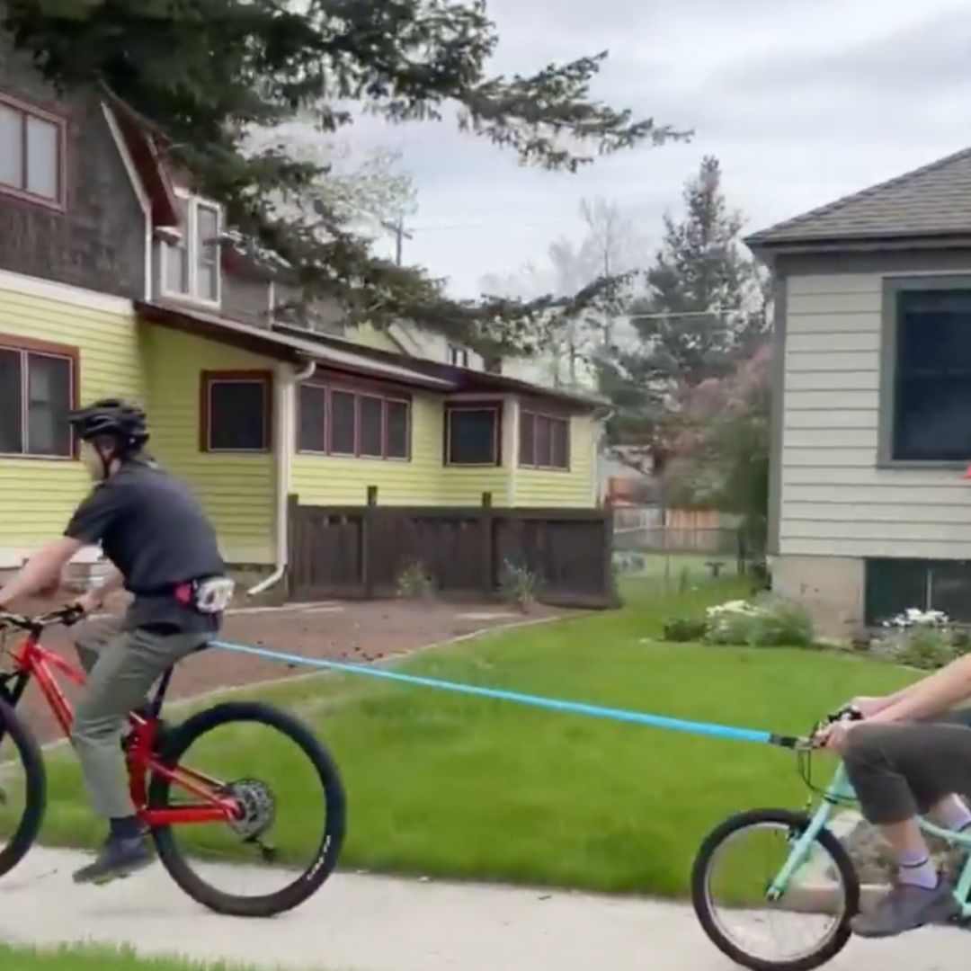 parent pulling their kid on a bike with a tow rope