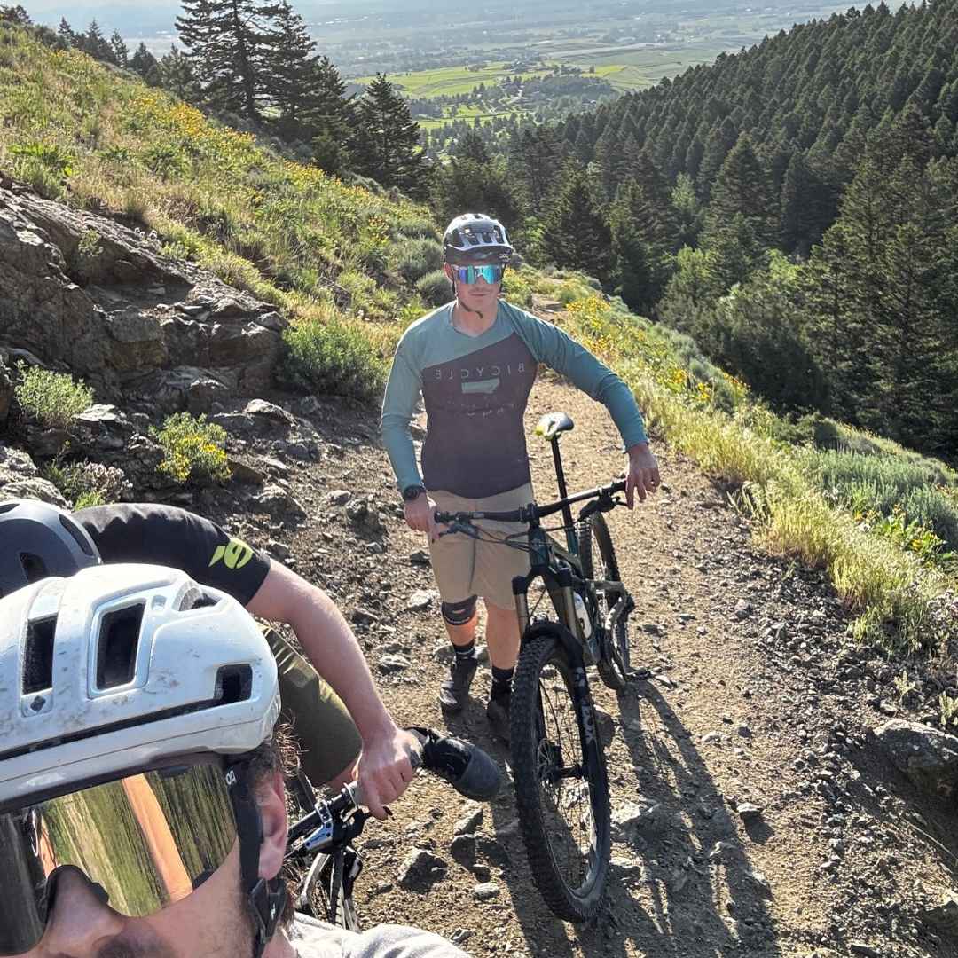 selfie picture of three mountain bikers on trail with pine trees in background